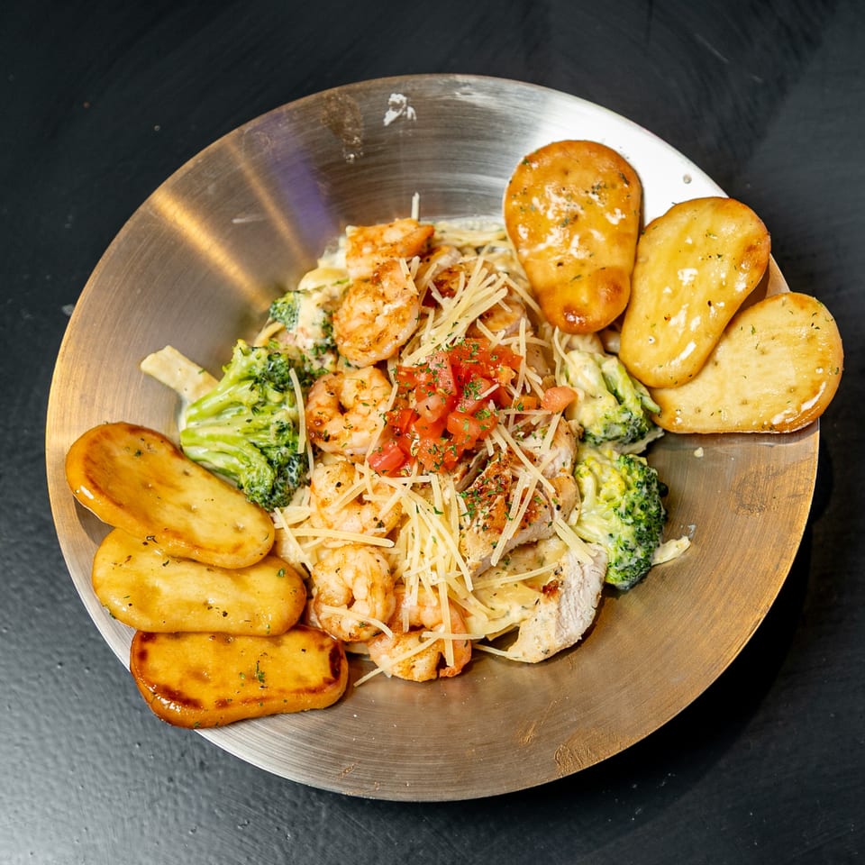 Creamy pasta with shrimp, chicken, broccoli, diced tomatoes, shredded cheese, and garlic bread.
